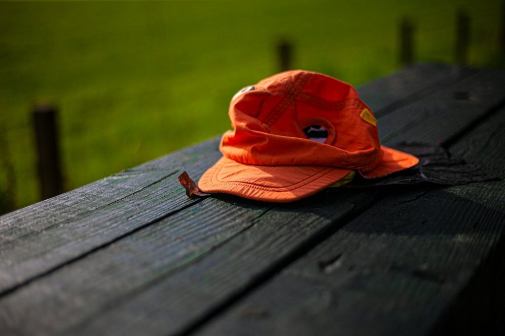 An orange hat rests on a picnic table.
