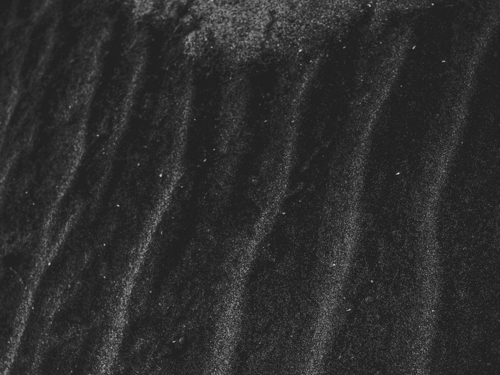 a black and white photo of sand and water