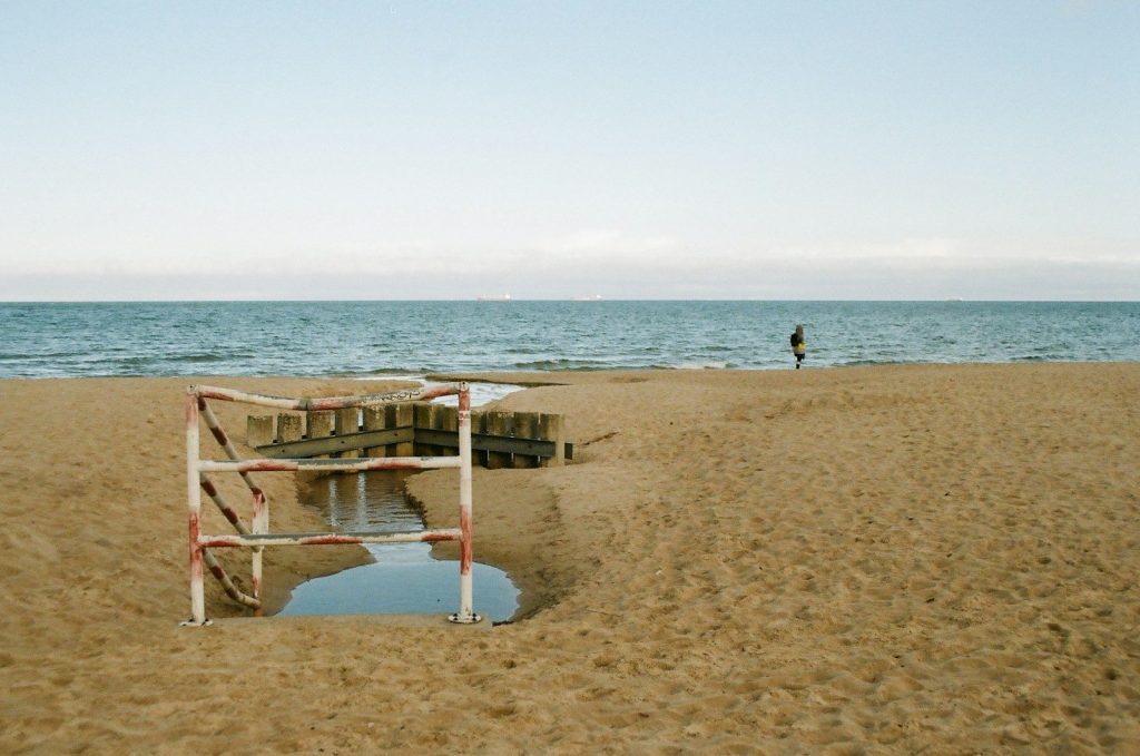 a man standing on a beach next to a body of water