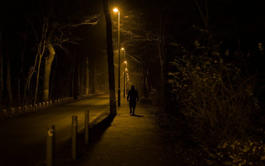 Person walking down a dimly lit path at night.