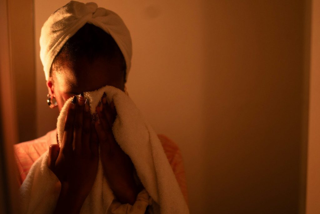 Woman dries her face with a white towel.