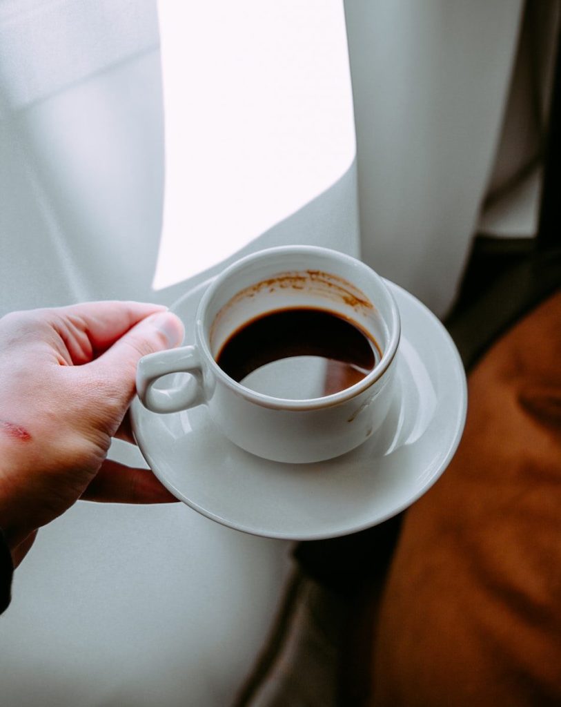 person holding white ceramic mug with black liquid