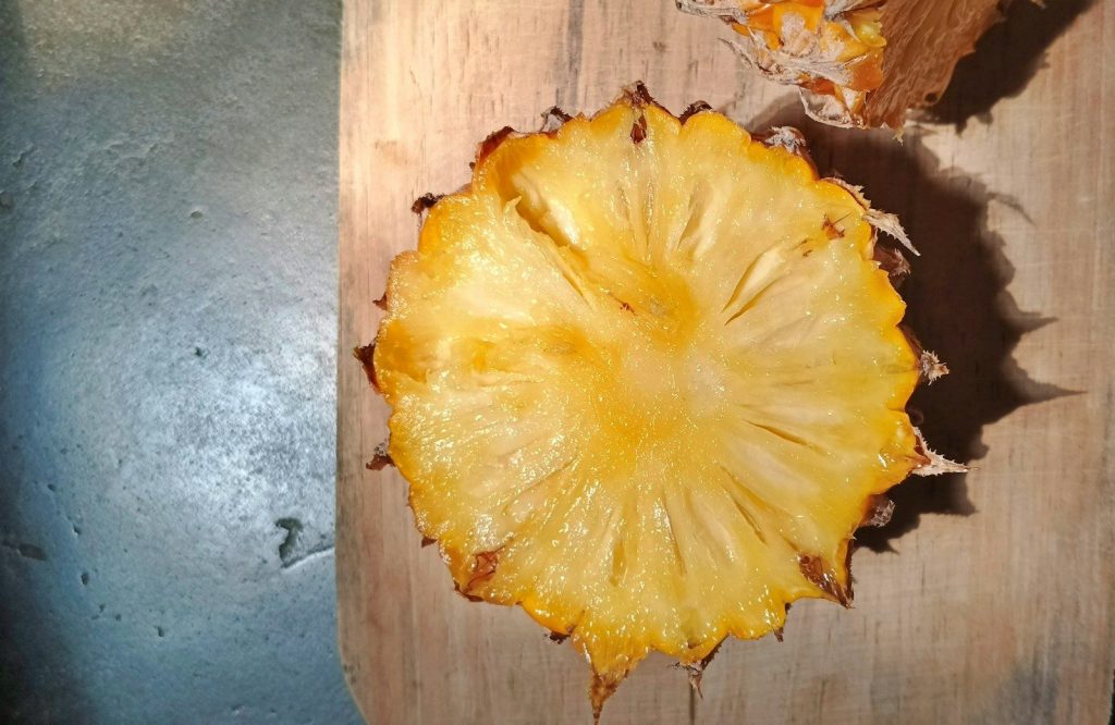 Slice of ripe pineapple on a wooden cutting board