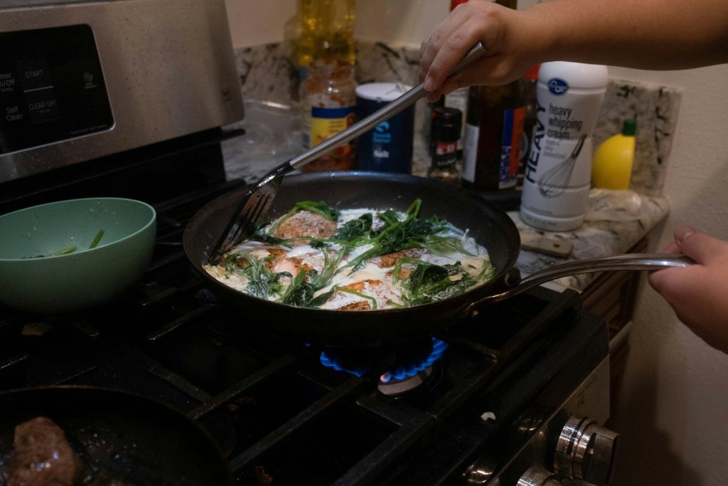 a person cooking food in a pan on the stove