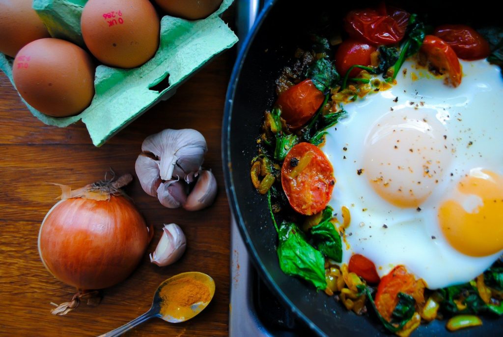 A pan filled with eggs and vegetables on top of a table