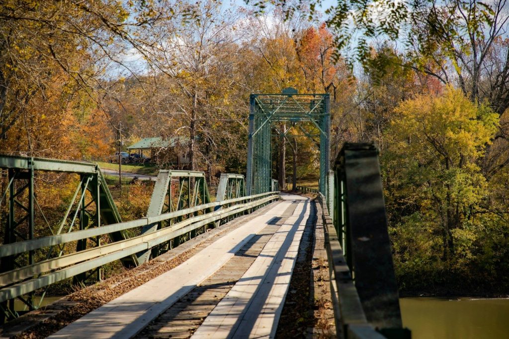 Green metal bridge over a river in autumn
