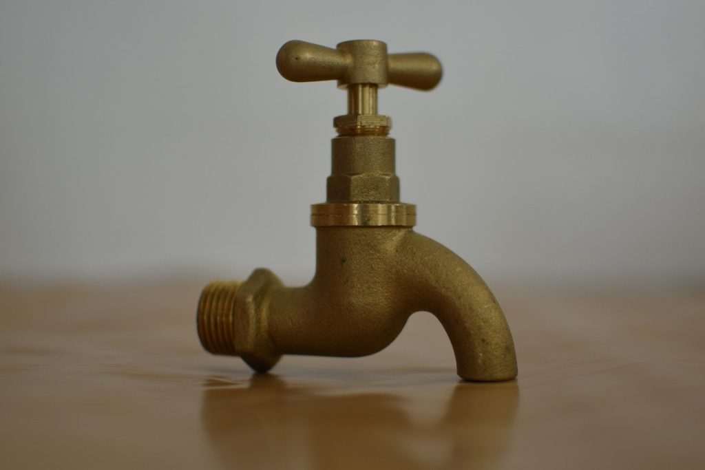 a brass faucet on a wooden table