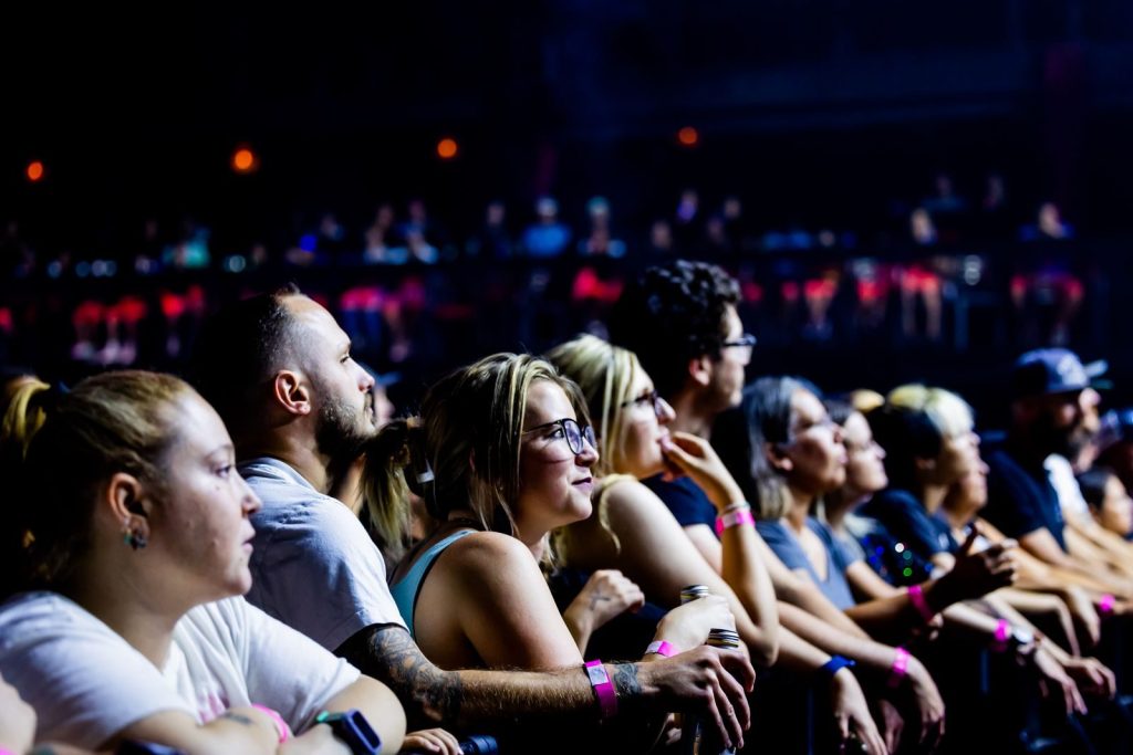 A lively crowd enjoys a live concert indoors, capturing the energy and excitement of the event.