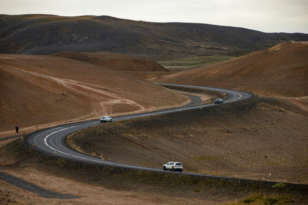 a group of cars driving down a road in a hilly area