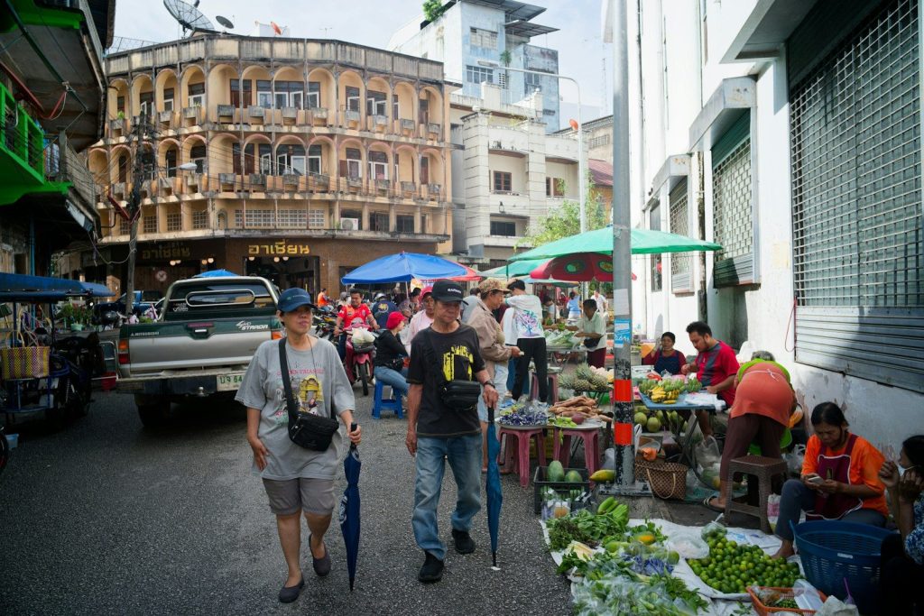 People walk past market stalls on a street.