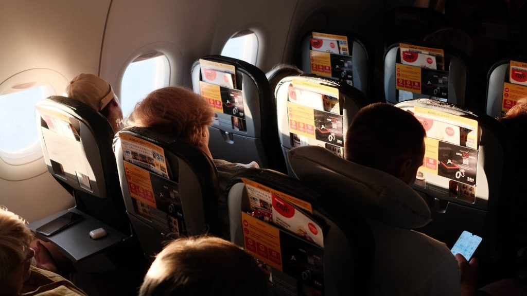 Passengers seated inside an airplane cabin during a flight.