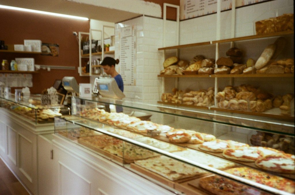 Bakery display with baked goods and staff member