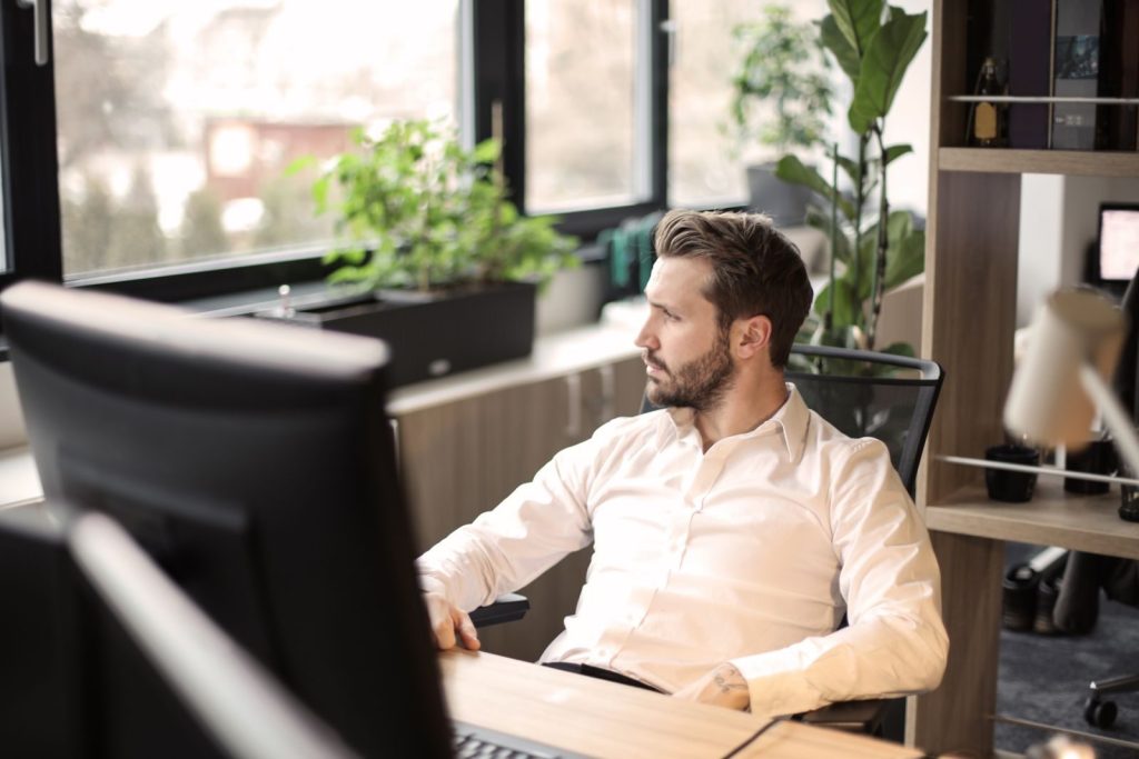 Man in white shirt working in a modern office with natural light.