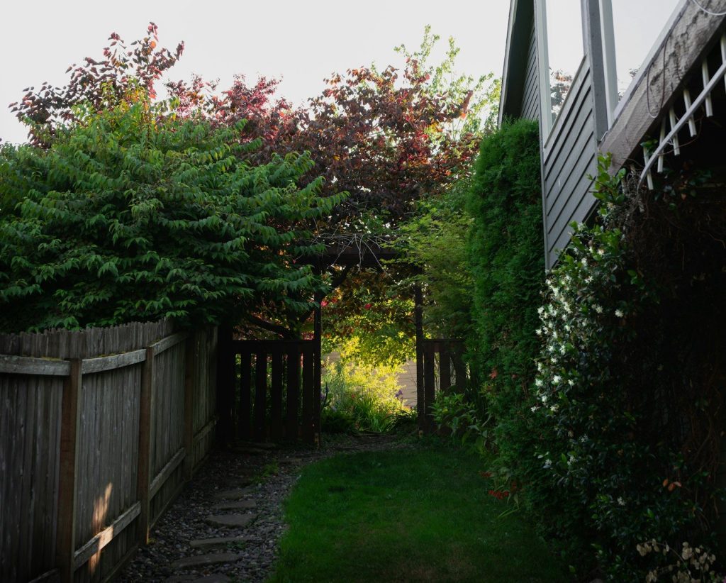 A wooden fence next to a house with a clock on it