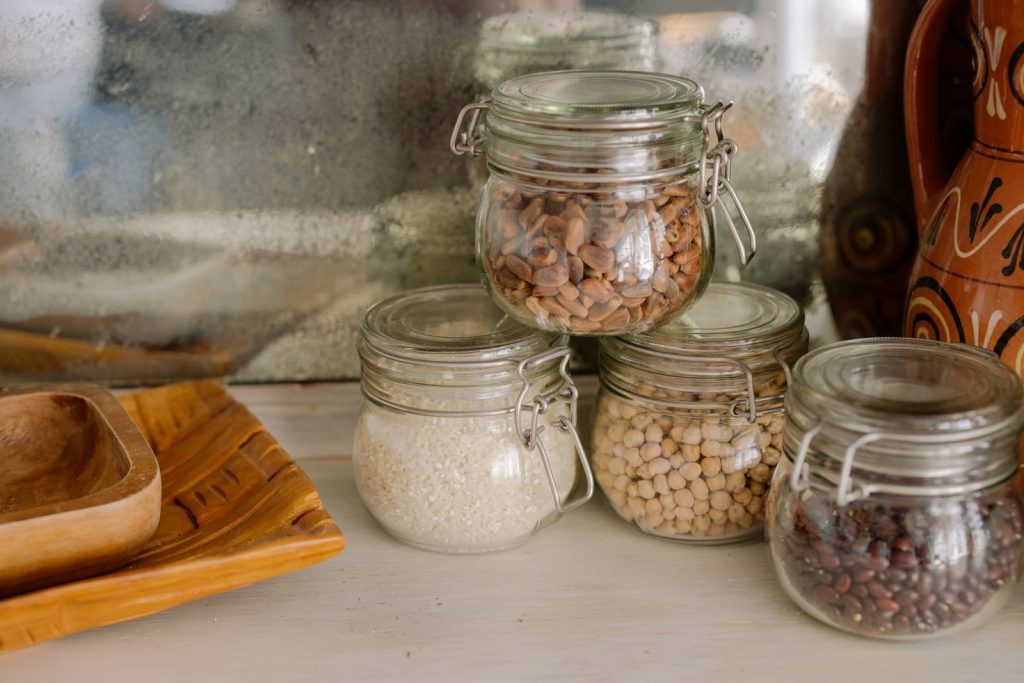 Elegant kitchen scene with glass jars of chickpeas, rice, and beans on a wooden counter.
