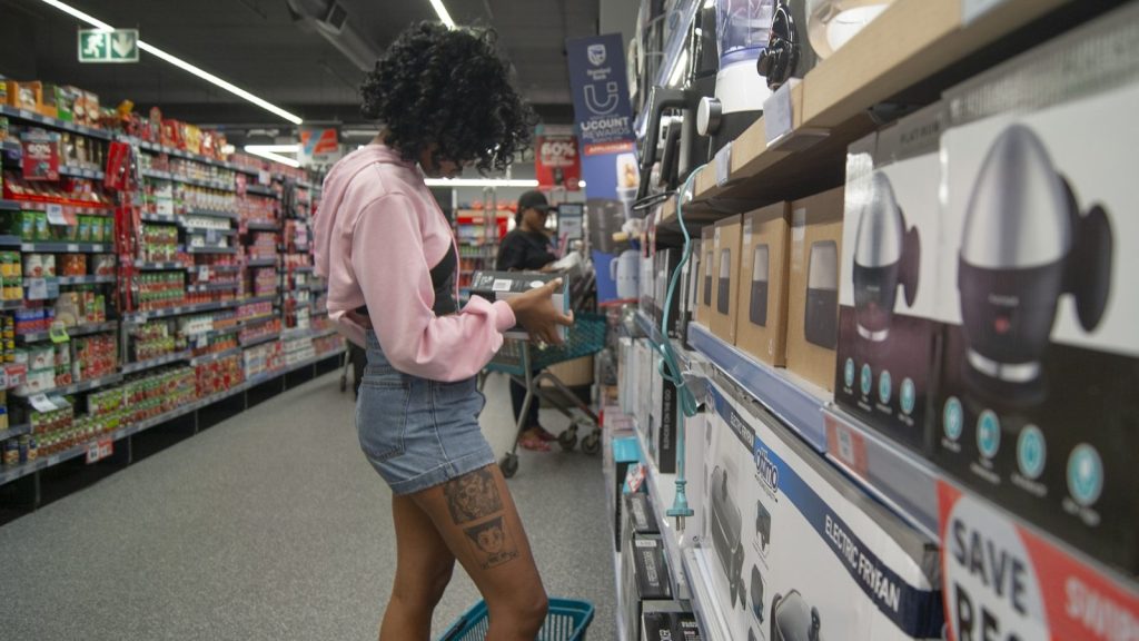 Woman browsing appliances in a supermarket aisle.