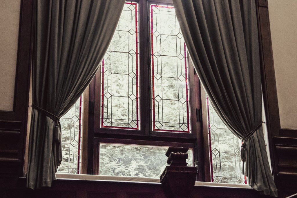 a window with curtains and a clock in front of it
