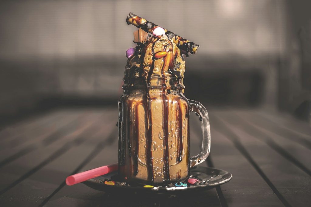 A decadent milkshake topped with chocolate drizzle and cookies.
