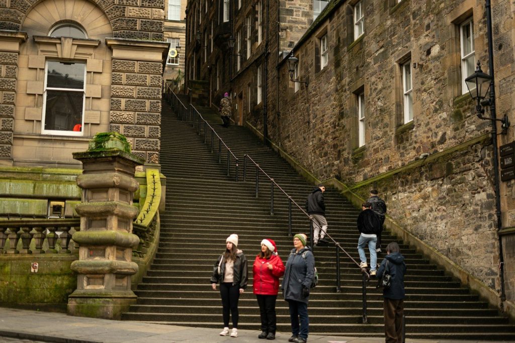 People ascend a wide stone staircase between old buildings.