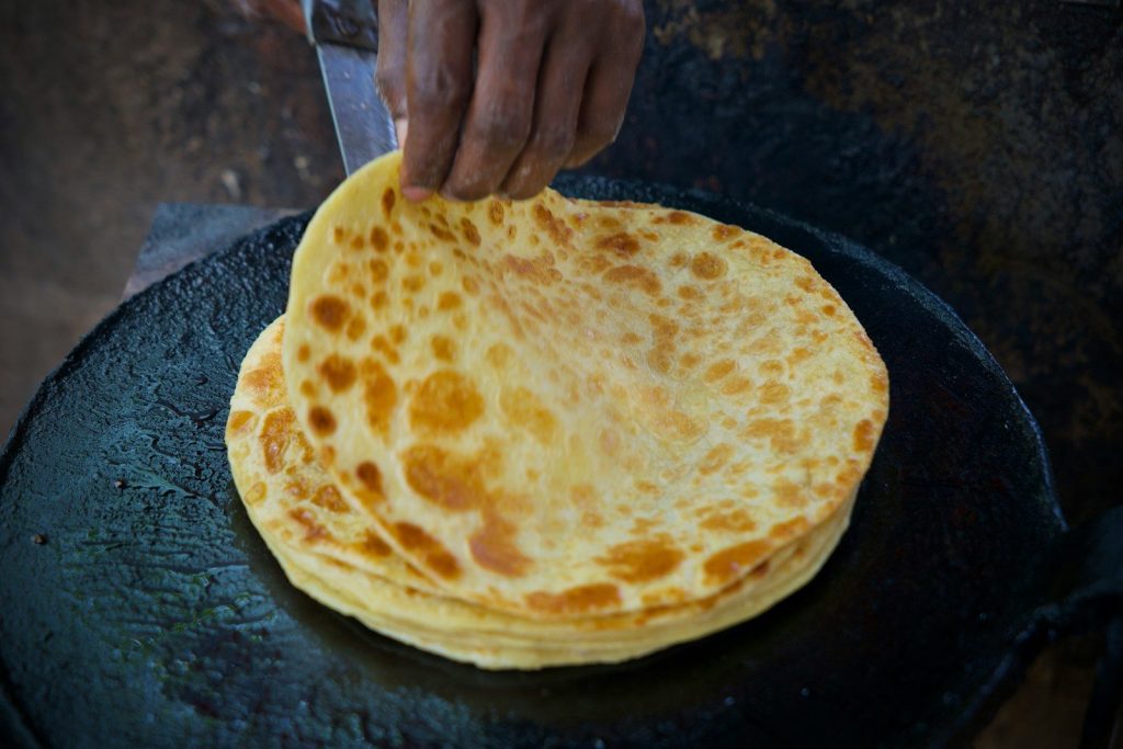 Cooking paratha on a hot, flat griddle.