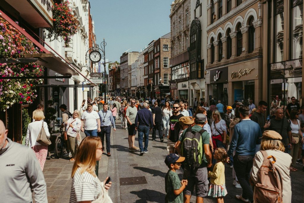 People walking on a busy city street with shops.