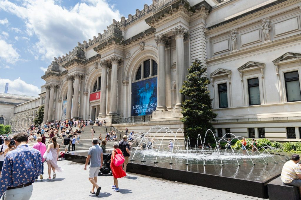 People on steps of metropolitan museum of art with fountain.