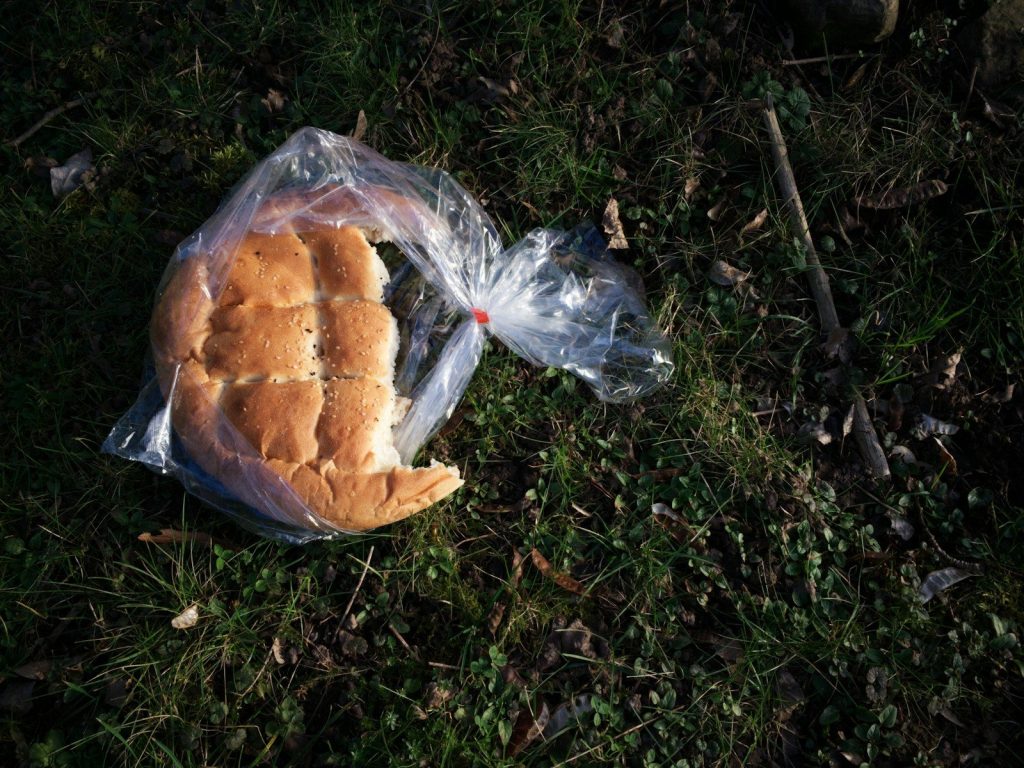 a sandwich wrapped in plastic sitting on the ground