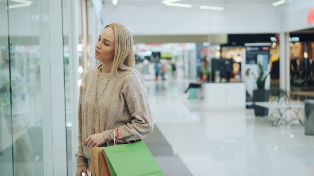 Woman looking into a shop window with shopping bags