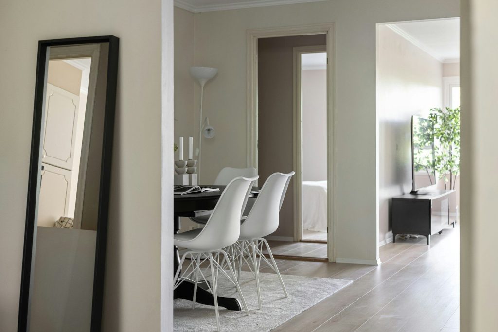 A dining room with a table and chairs and a mirror