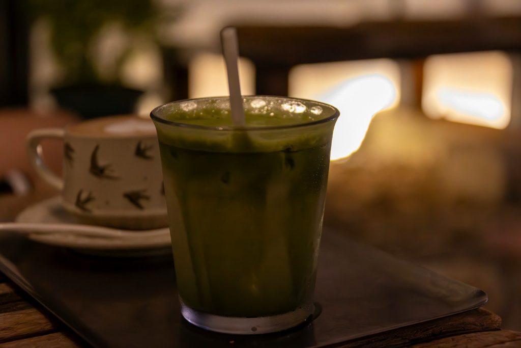 A green beverage with ice and a straw.
