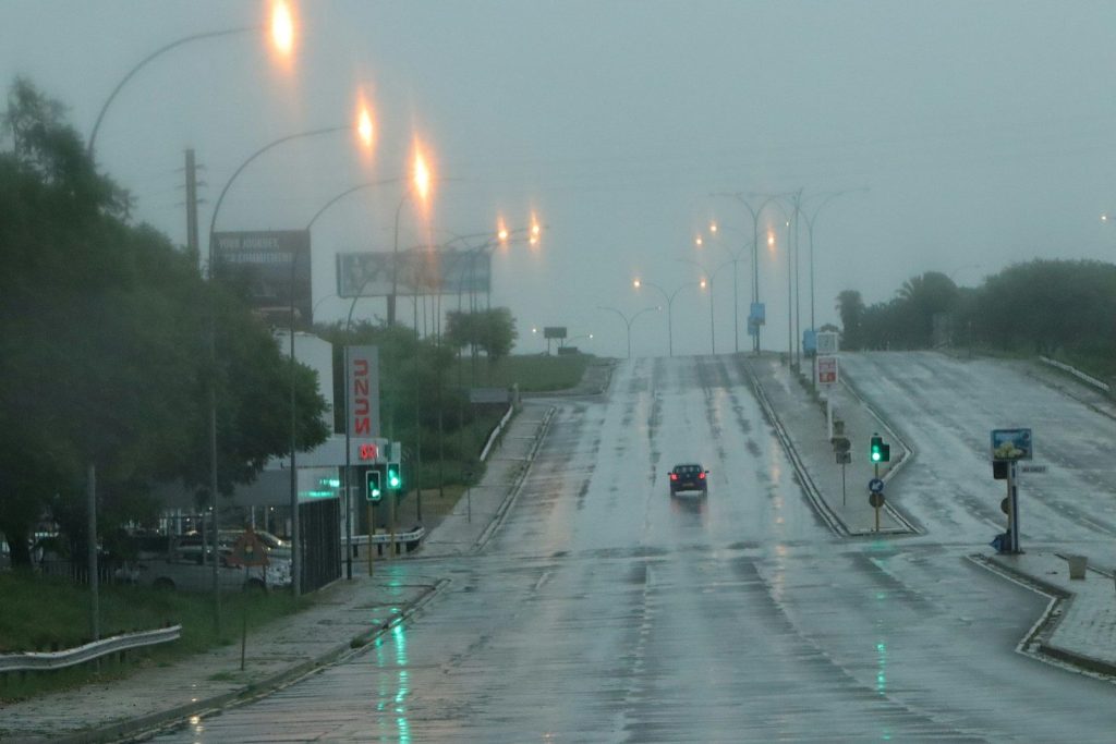 A wet road with traffic lights and streetlights.