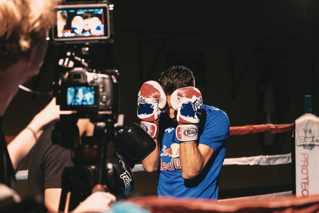 man in blue tank top wearing black and white boxing gloves