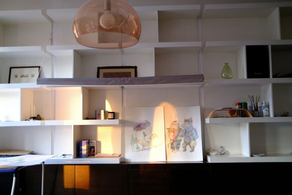 Sunlight illuminates a white shelving unit with decorative objects.