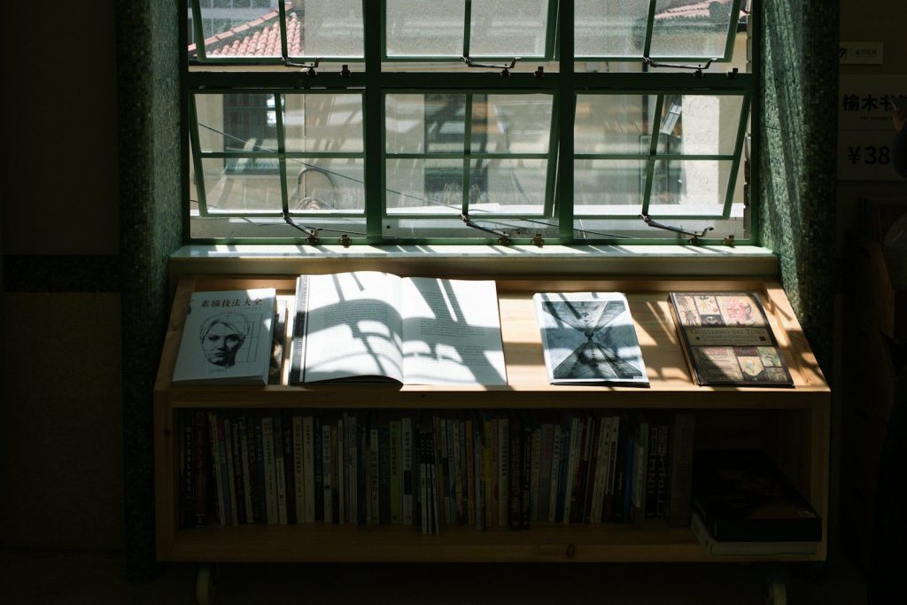 a bookshelf with several books on it in front of a window