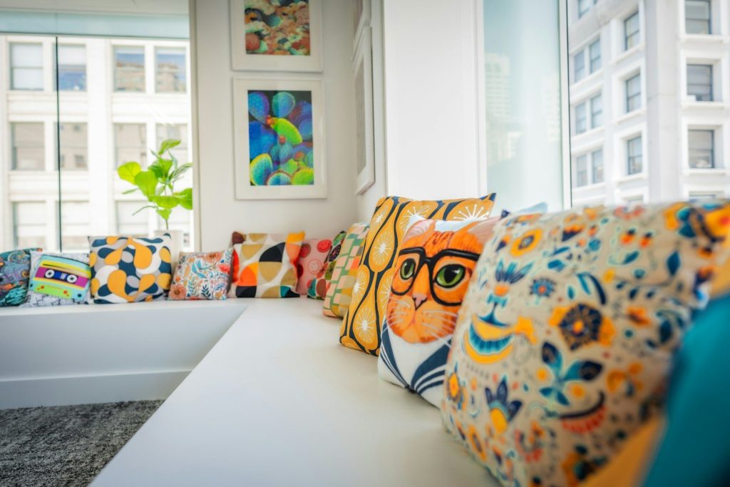Patterned pillows, including a cat, on a white window bench.