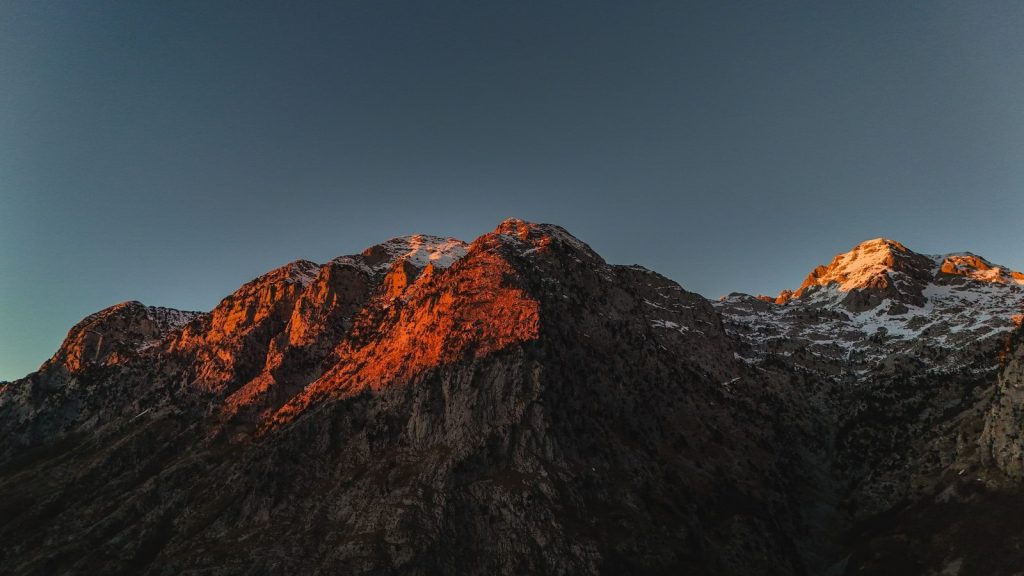 Sunlight illuminates rugged mountain peaks at dawn.