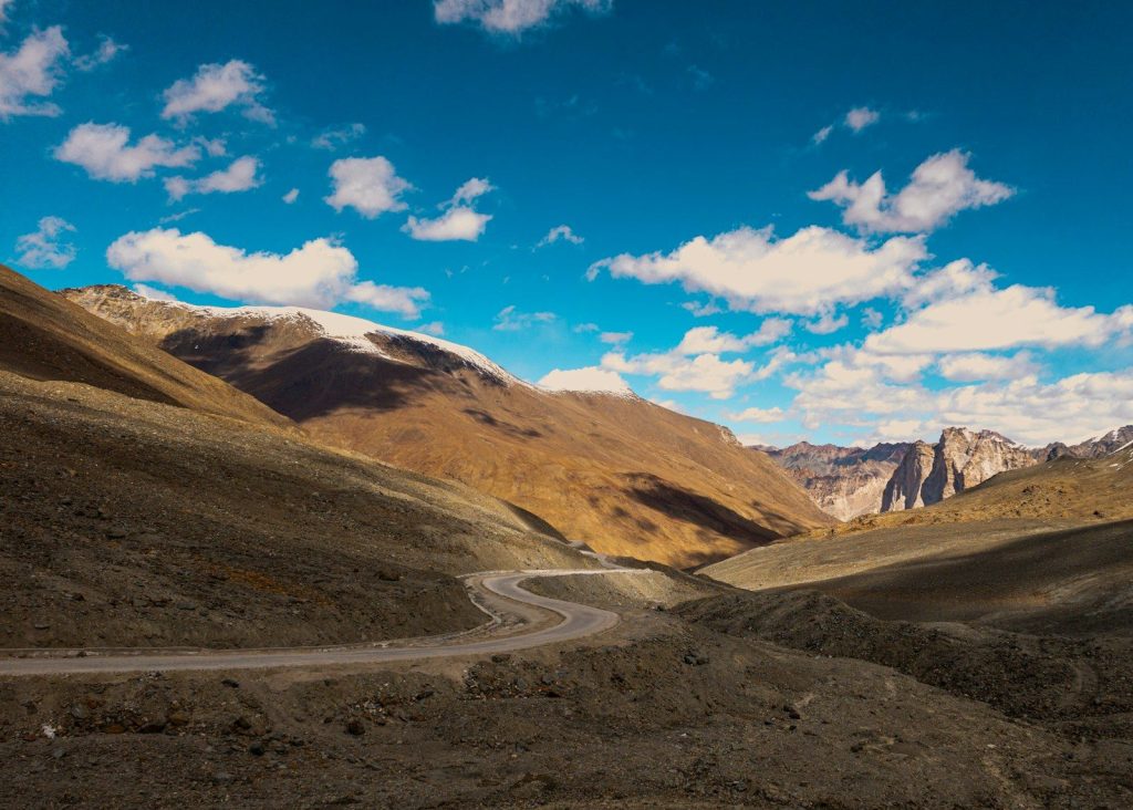 Arid mountains and a winding road under a blue sky.