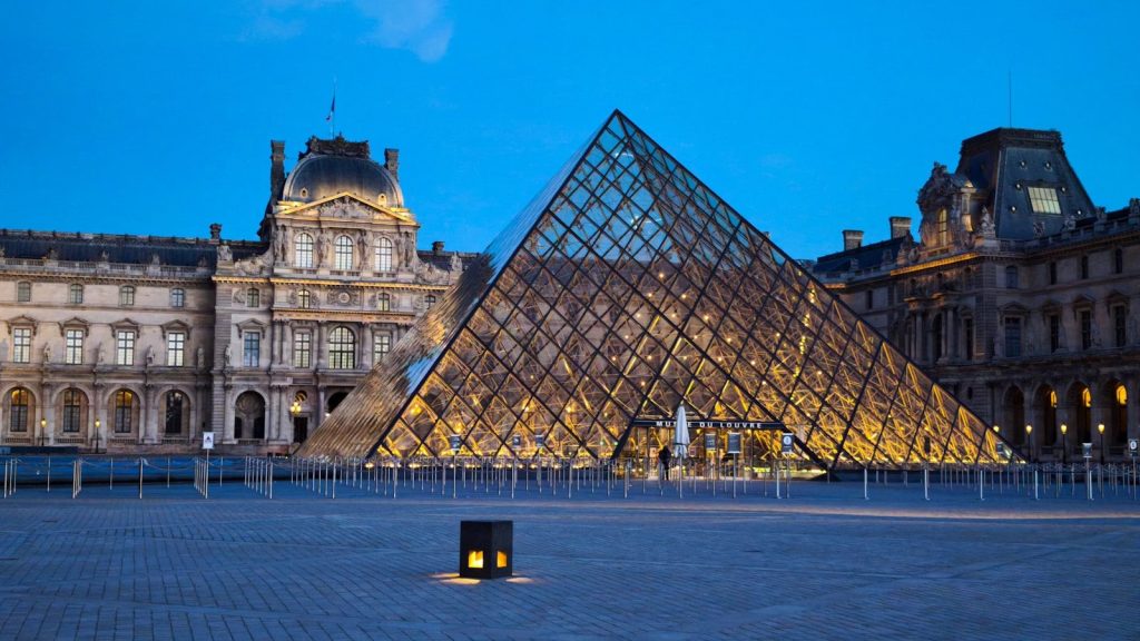 Louvre museum pyramid illuminated at dusk