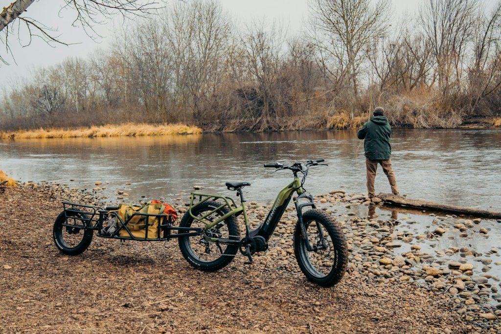a man standing next to a bike near a river