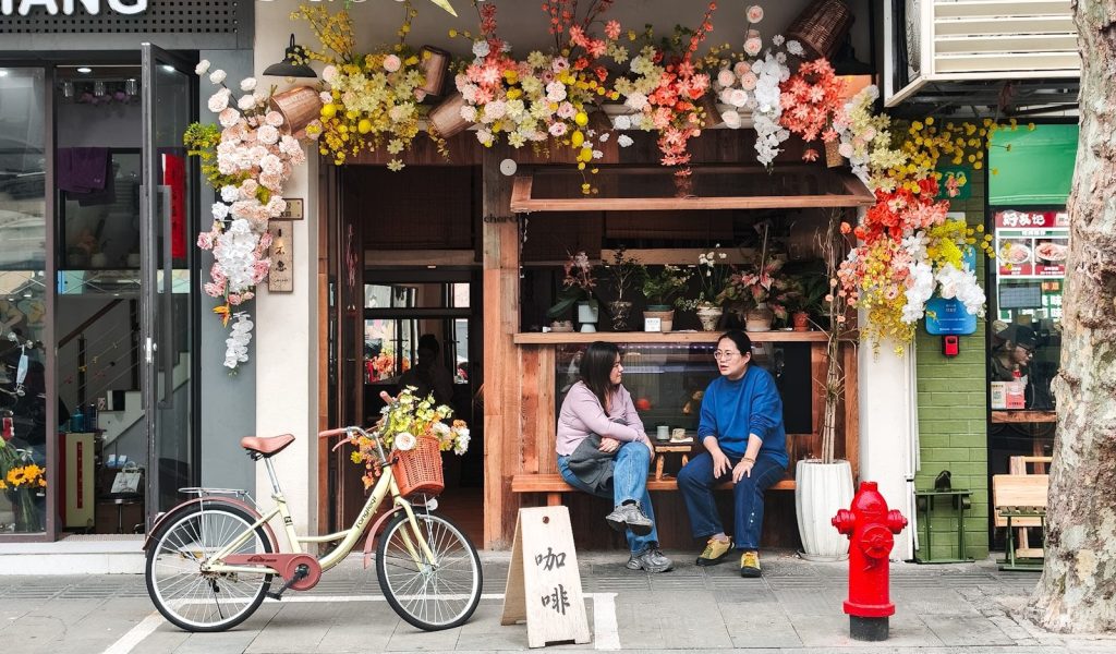 Two women sitting outside a flower shop with a bicycle