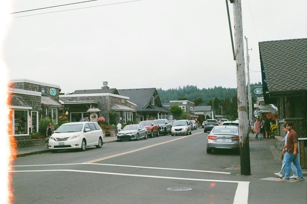 Street scene with cars and shops on a cloudy day.