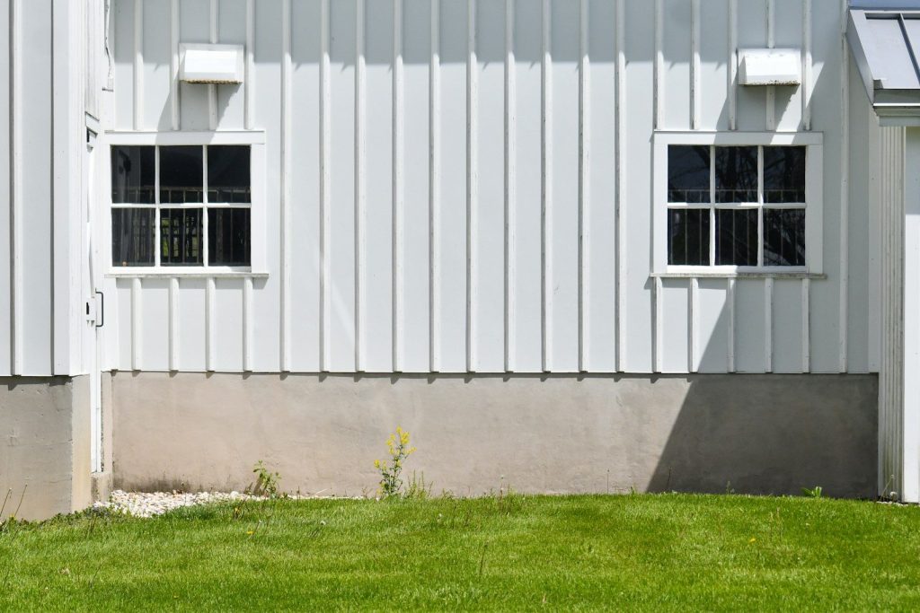 White wooden building with two windows and green grass.