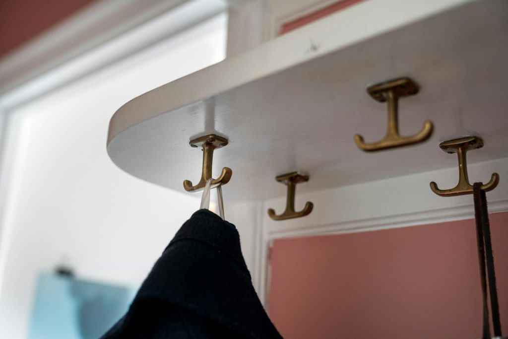 A coat rack with hooks and a coat hanging on it