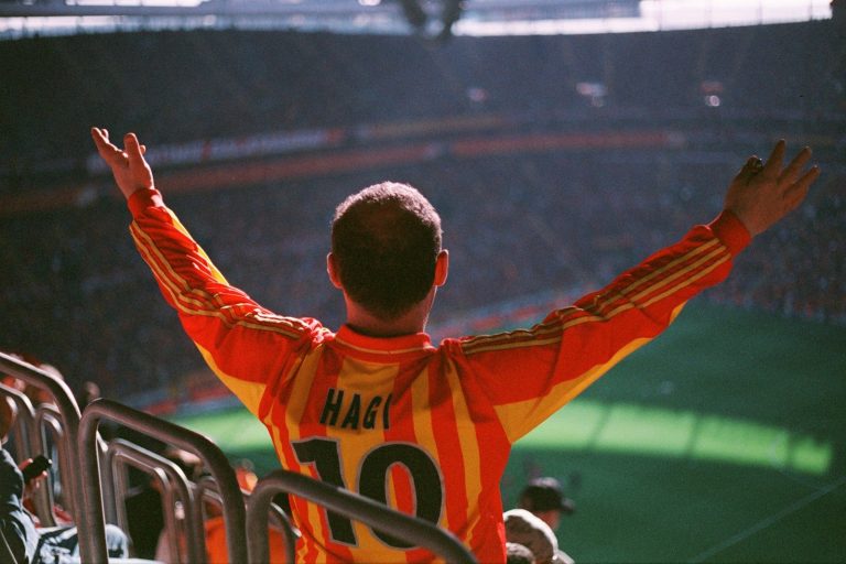 A man in an orange and yellow uniform at a soccer game