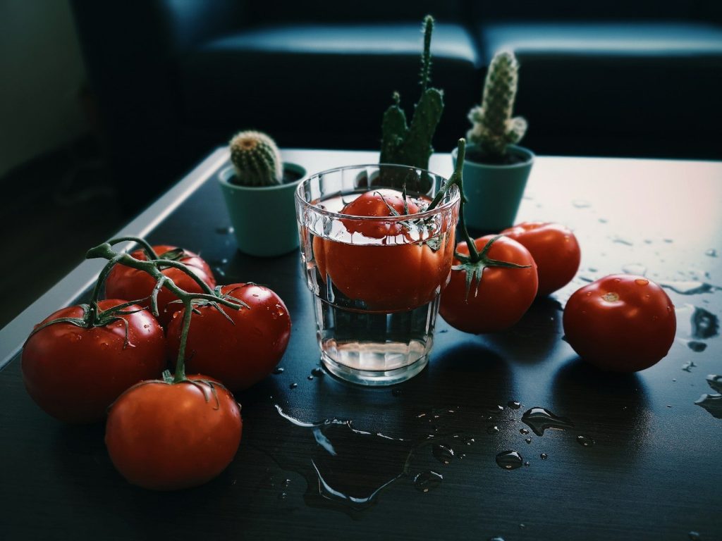 red tomato fruit beside clear drinking glass