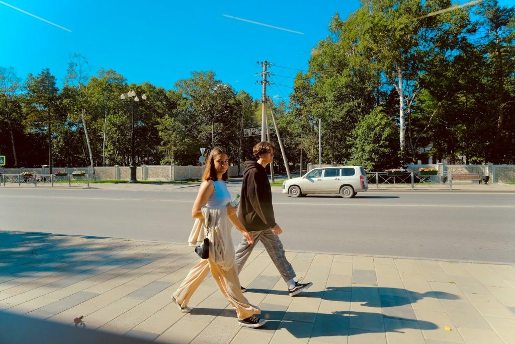 Two people walking across a street on a sunny day