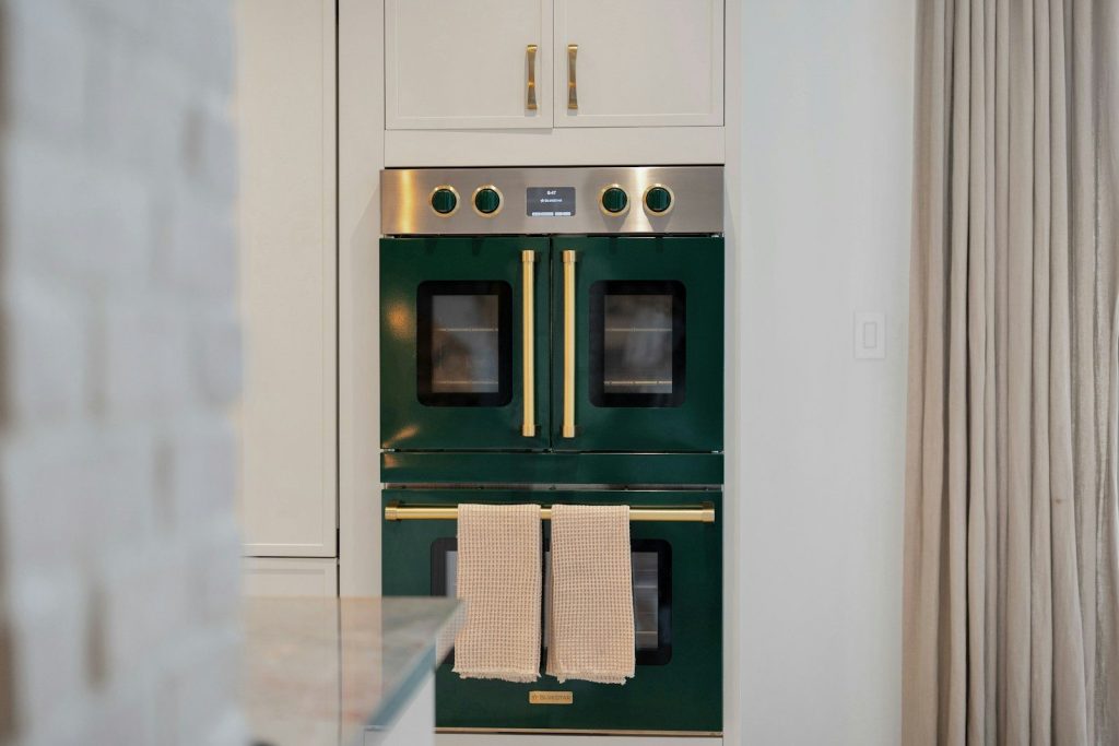 Stylish dark green double oven with brass handles and towels.