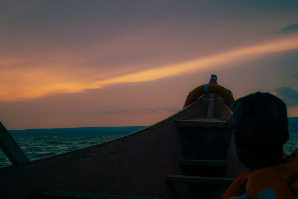 A boat glides across water during sunset.