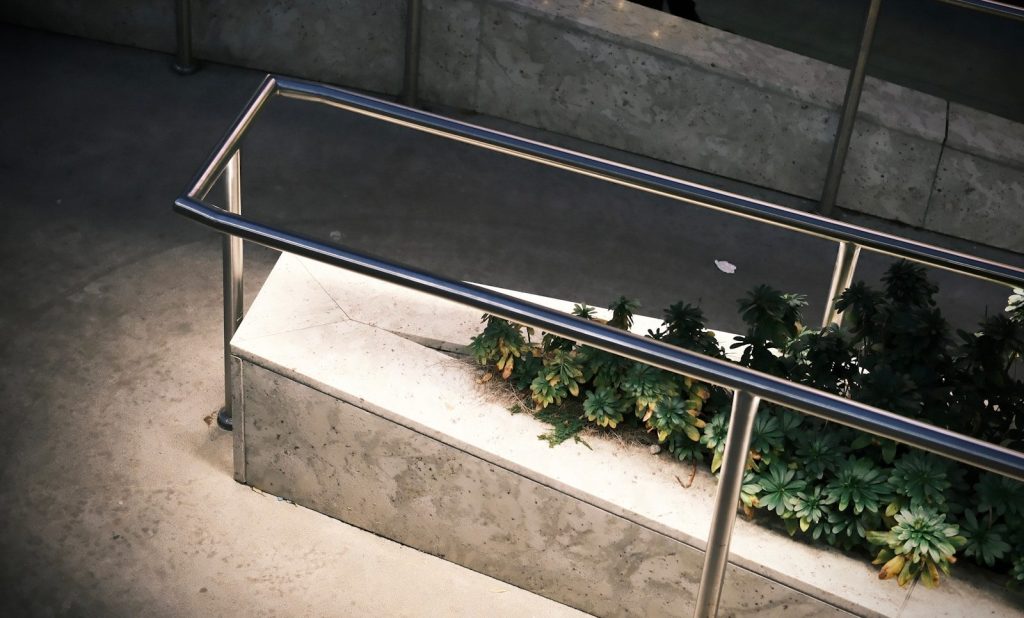 Modern metal railing beside concrete planter with plants