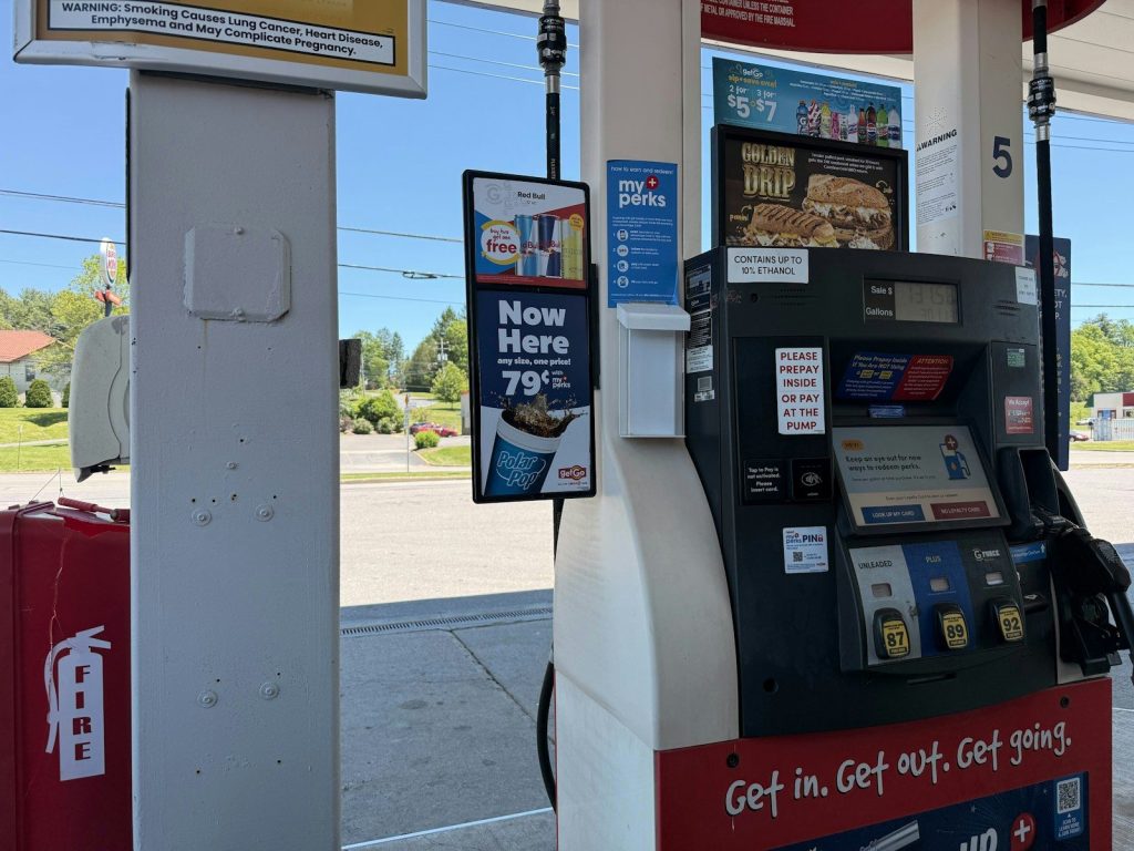 A gas pump at a station on a sunny day.